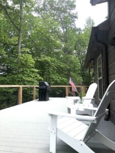 Showing deck with outdoor propane grill and 2 patio adirondack chairs