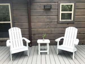 2 white adirondack chairs and small deck with flower on table